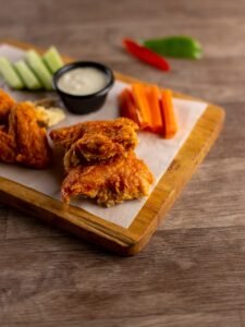 Crispy chicken wings with dipping sauce and vegetables