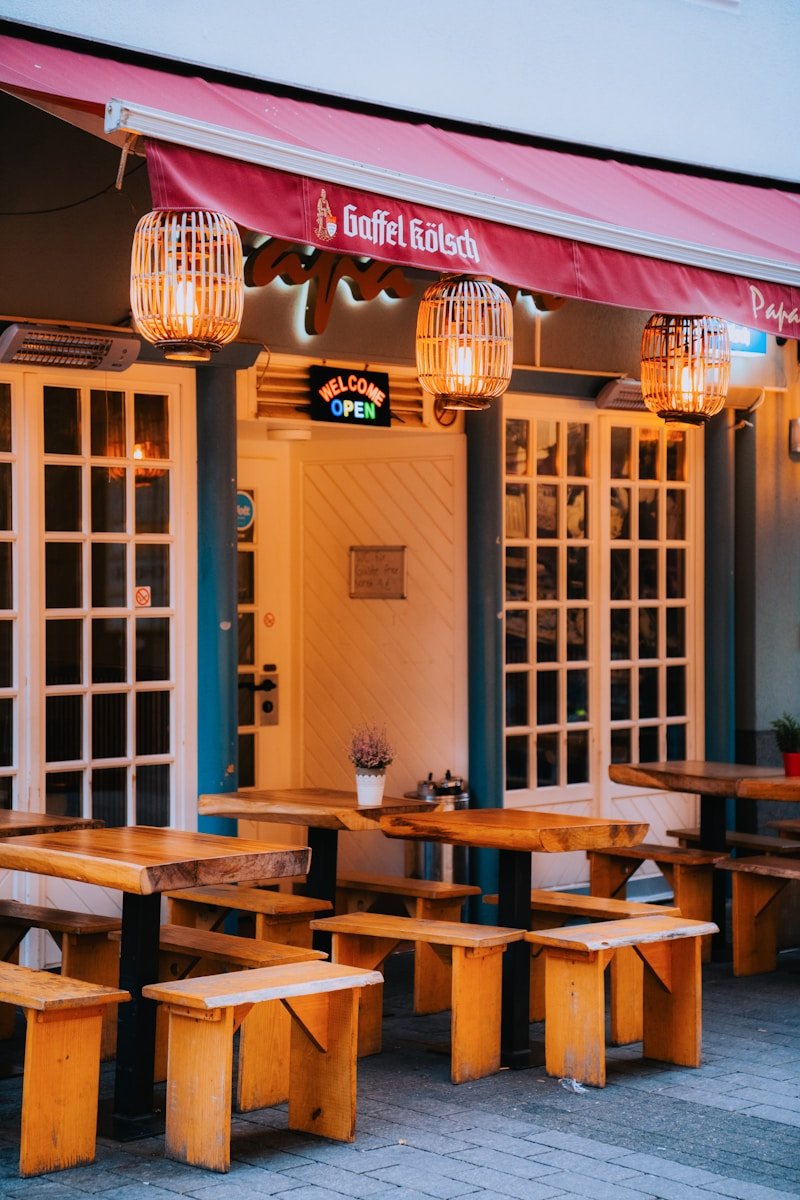 A row of wooden tables sitting outside of a restaurant